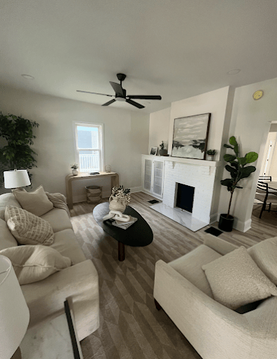Cozy neutral living room with white sofas, fireplace, and potted plants