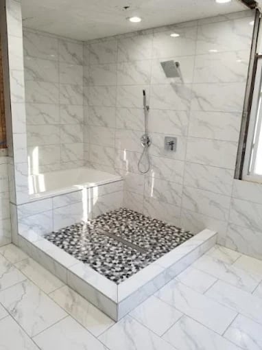 Modern marble shower with pebble floor and glass shower head