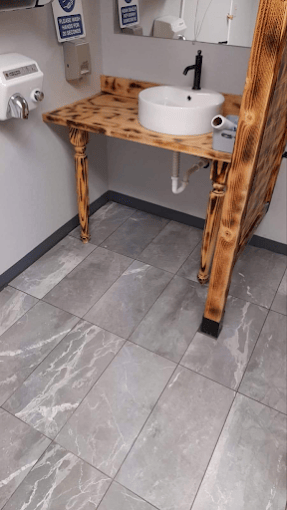 Rustic wooden vanity with round white sink on gray tile bathroom floor