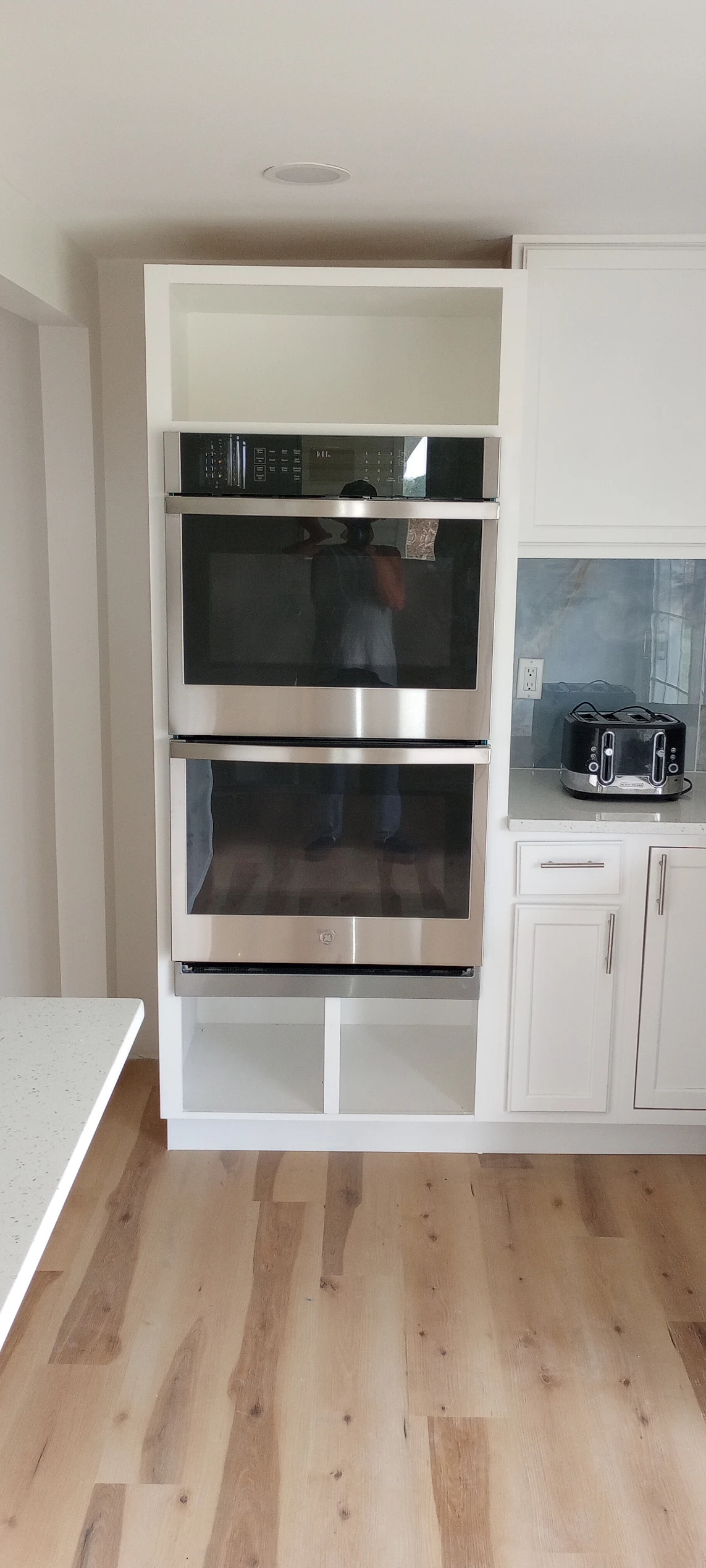 Modern kitchen with double wall ovens and white cabinetry